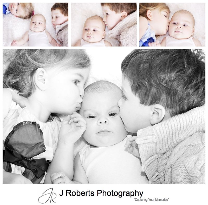 Baby boy being kissed by his older siblings - baby portrait photography sydney